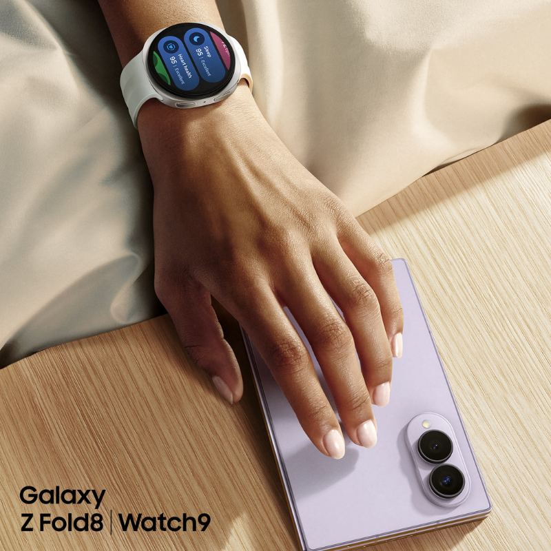 Samsung Galaxy Z Fold8 položený na stole s ruka nosící chytré hodinky Galaxy Watch9