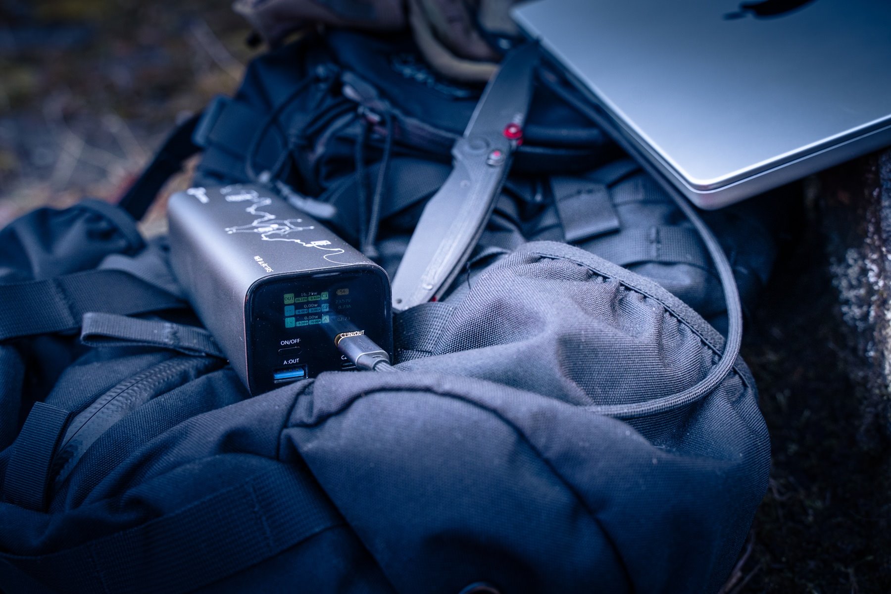 Powerbanka Tactical Squad připojená k notebooku na batohu během kempování v přírodě